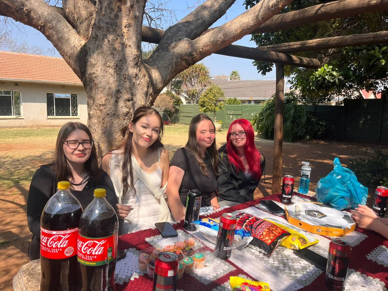 Learners at the picnic table under the tree at St. Ronald's Homeschool Spring Picnic