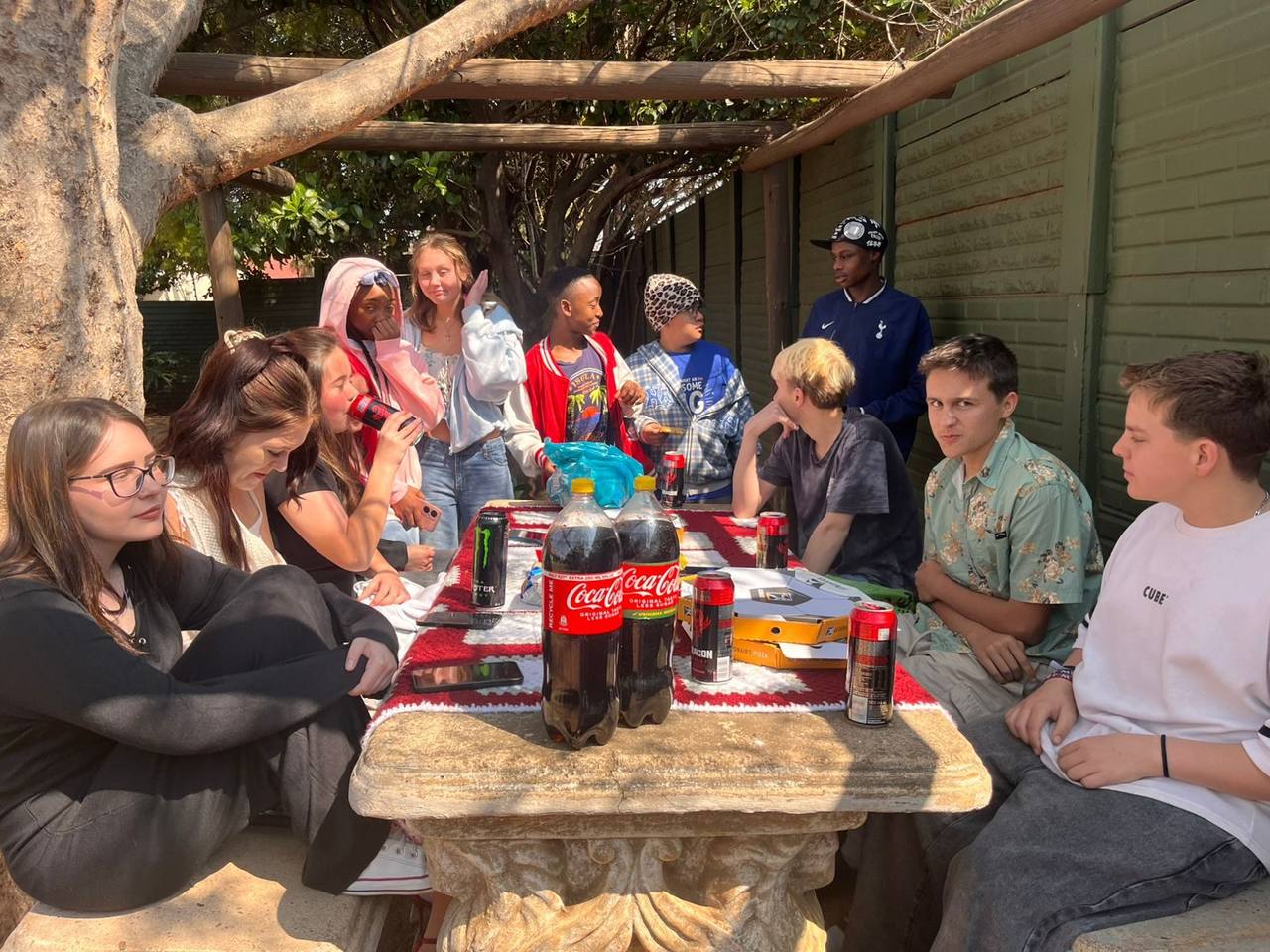 Picnic gathering under the wooden pergola at St. Ronald's Homeschool